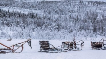 This image is of Tromso city. There is a sledge in the image on mountain Covered in snow.